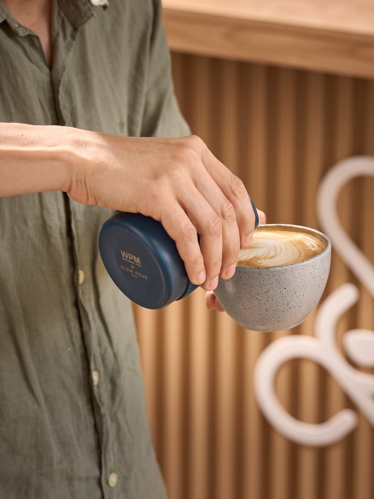 A barista pours a latte with latte art into a ceramic cup